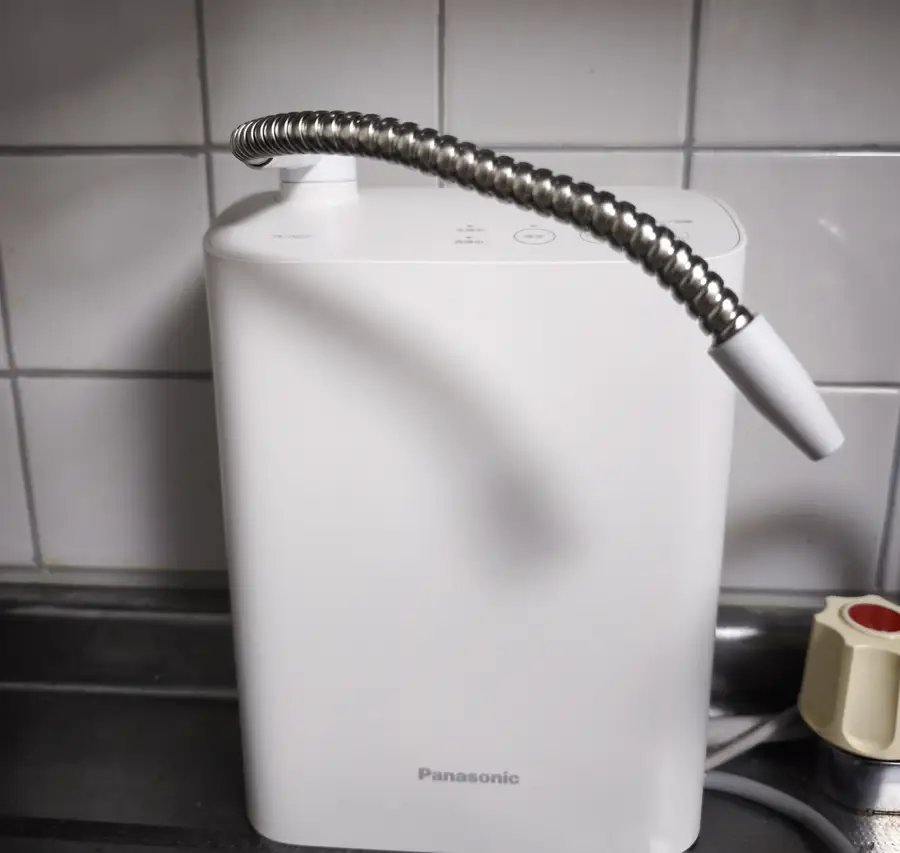 キッチンのシンク脇に設置した TK-AS32 の本体全体。白い縦長のボディからシャワーホースが伸びている